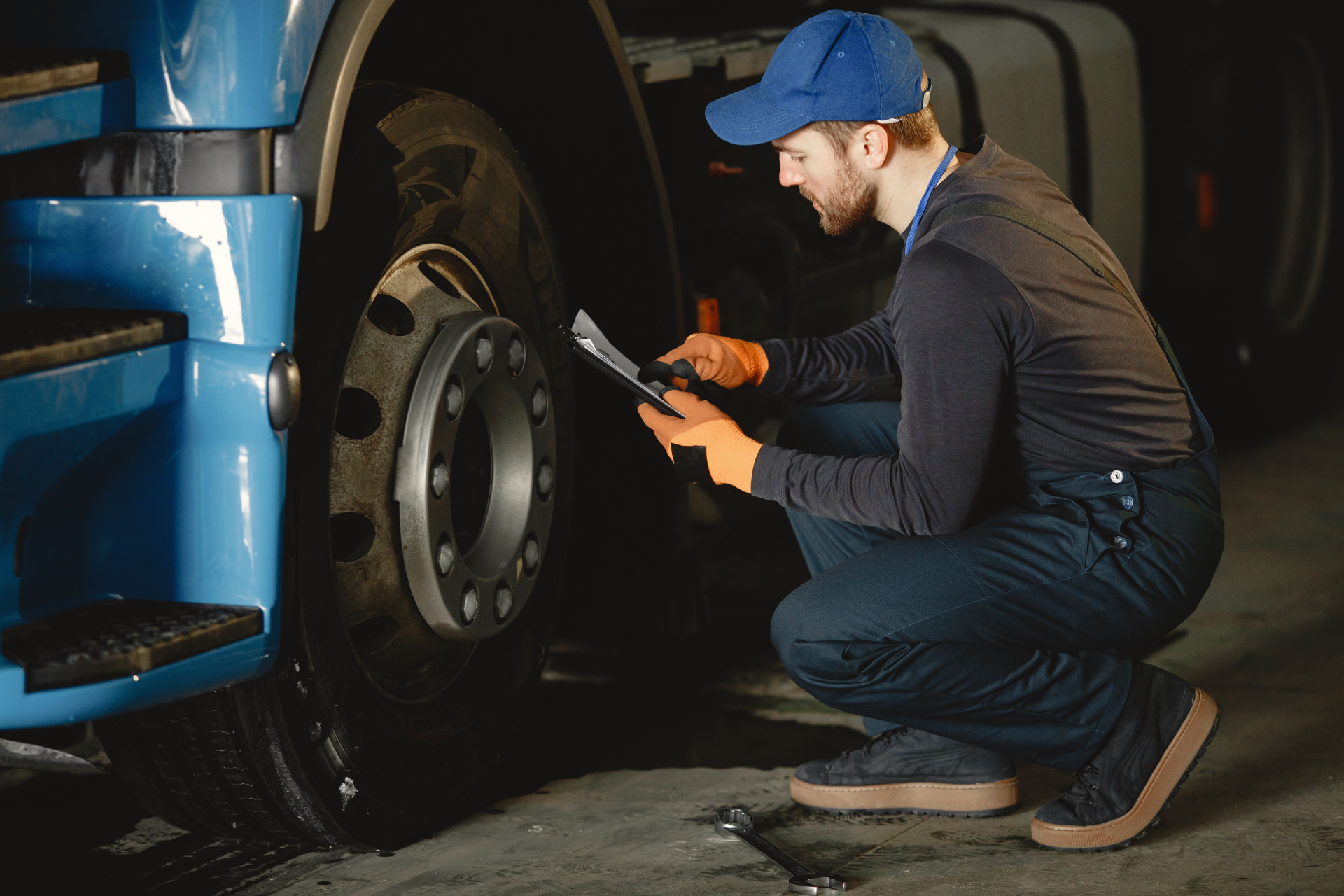Preventive maintenance inspection on a small fleet truck Fleet mechanic inspecting a heavy truck wheel with a tablet checklist